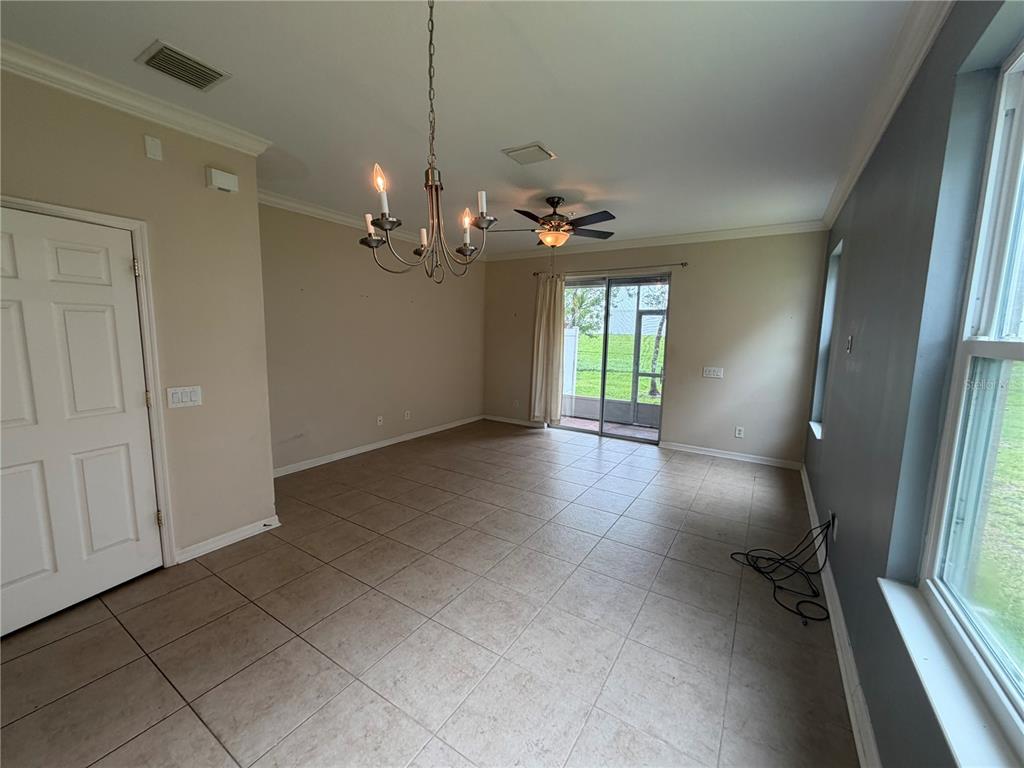 An empty dining room features tile flooring, a chandelier, a ceiling fan, and sliding glass doors — 1146 GRANTHAM DRIVE, SARASOTA, FL