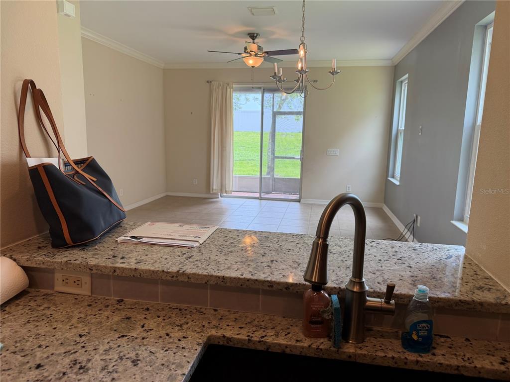 A kitchen view looking over a granite countertop into an open living area with sliding doors — 1146 GRANTHAM DRIVE, SARASOTA, FL
