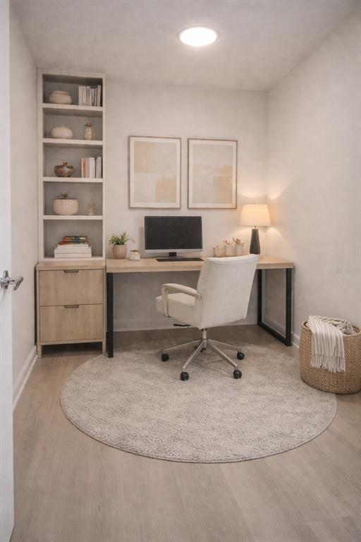 A home office features a built-in bookshelf, a wooden desk, and a round area rug — 5587 MILLENIA BOULEVARD UNIT 207, ORLANDO, FL