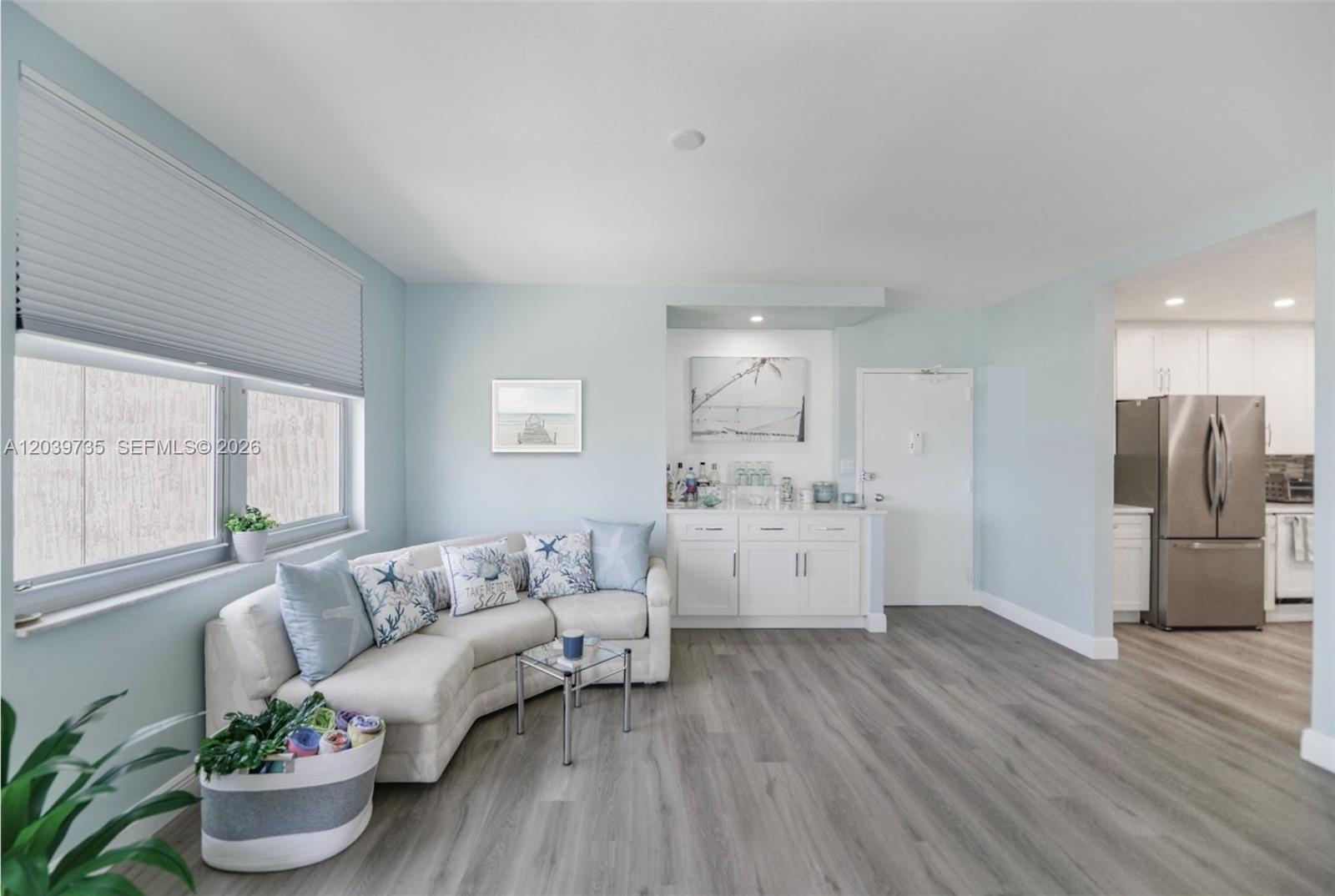 A living room features light blue walls, a curved sofa, and a wet bar area — 1985 S Ocean Dr # 8P, Hallandale Beach FL 33009, HALLANDALE BEACH, FL