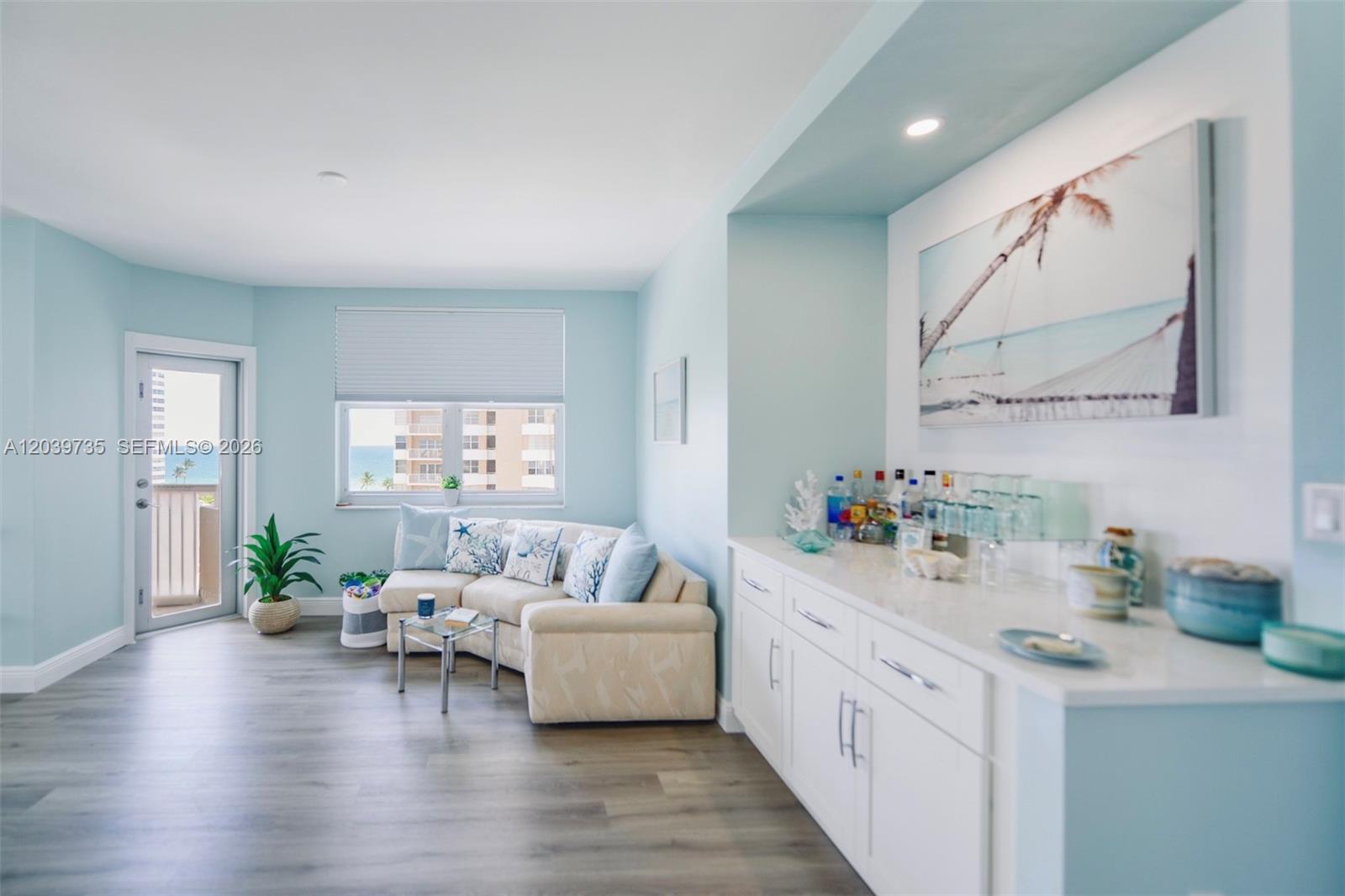 A living room features light blue walls, a sectional sofa, and a built-in wet bar — 1985 S Ocean Dr # 8P, Hallandale Beach FL 33009, HALLANDALE BEACH, FL