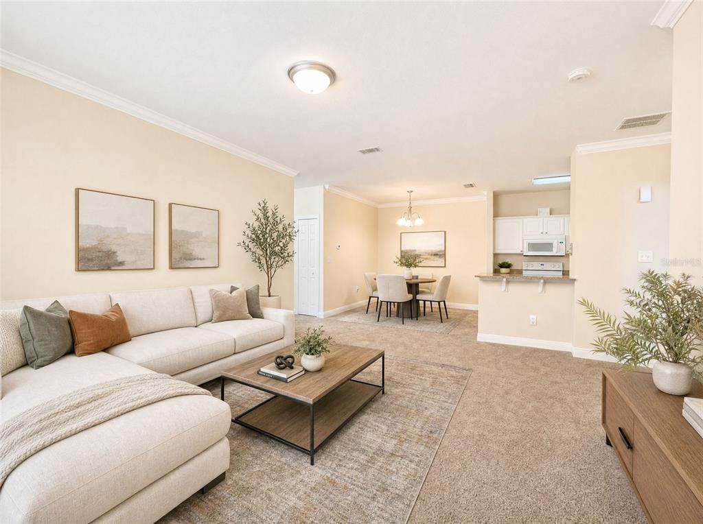 A living room with a sectional sofa, coffee table, and an adjacent dining area and kitchen — 143 SOUTHERN PECAN CIRCLE UNIT 201, WINTER GARDEN, FL