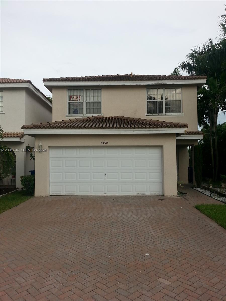 A two-story house features a beige stucco exterior, a tiled roof, and a white garage door — 5450 NW 94th Ter, Sunrise FL 33351, SUNRISE, FL