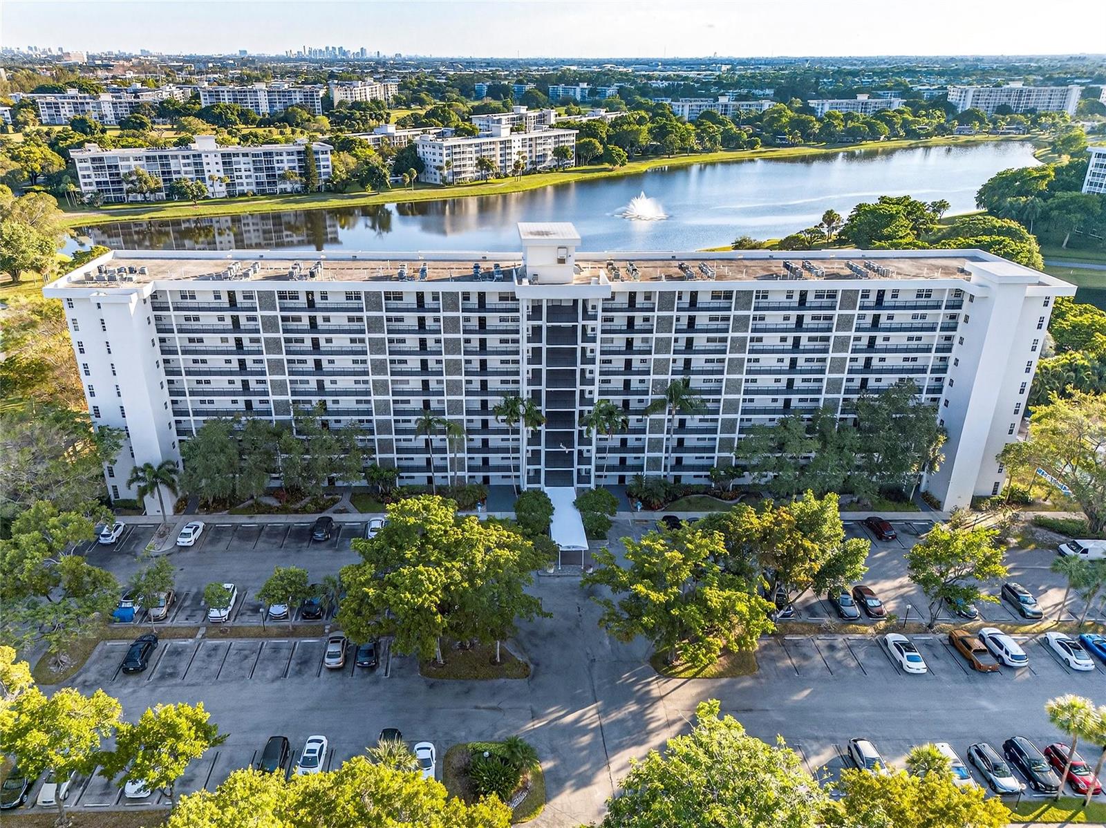 An aerial view shows a large apartment building with a parking lot and a lake — 2900 N Course Drive # 607, Pompano Beach FL 33069, POMPANO BEACH, FL