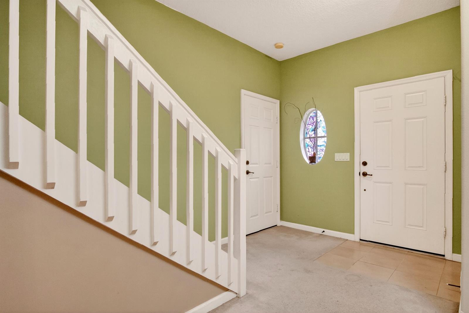 An entryway features green walls, a white staircase railing, two white doors, and an oval window — 1911 77th Drive, Vero Beach FL 32966, VERO BEACH, FL