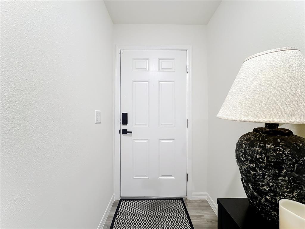 A white front door with a black smart lock stands in a small entryway — 120 BONITO WAY, KISSIMMEE, FL