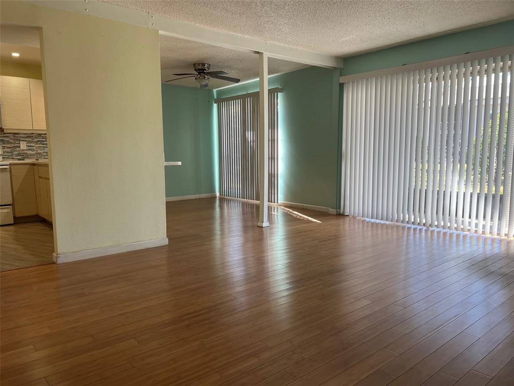 An open-concept living and dining area features light wood flooring and large vertical blinds — 2625 STATE ROAD 590 UNIT 2514, CLEARWATER, FL