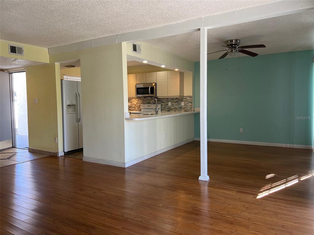 An open-concept living area features wood flooring, a kitchen pass-through, and a ceiling fan — 2625 STATE ROAD 590 UNIT 2514, CLEARWATER, FL