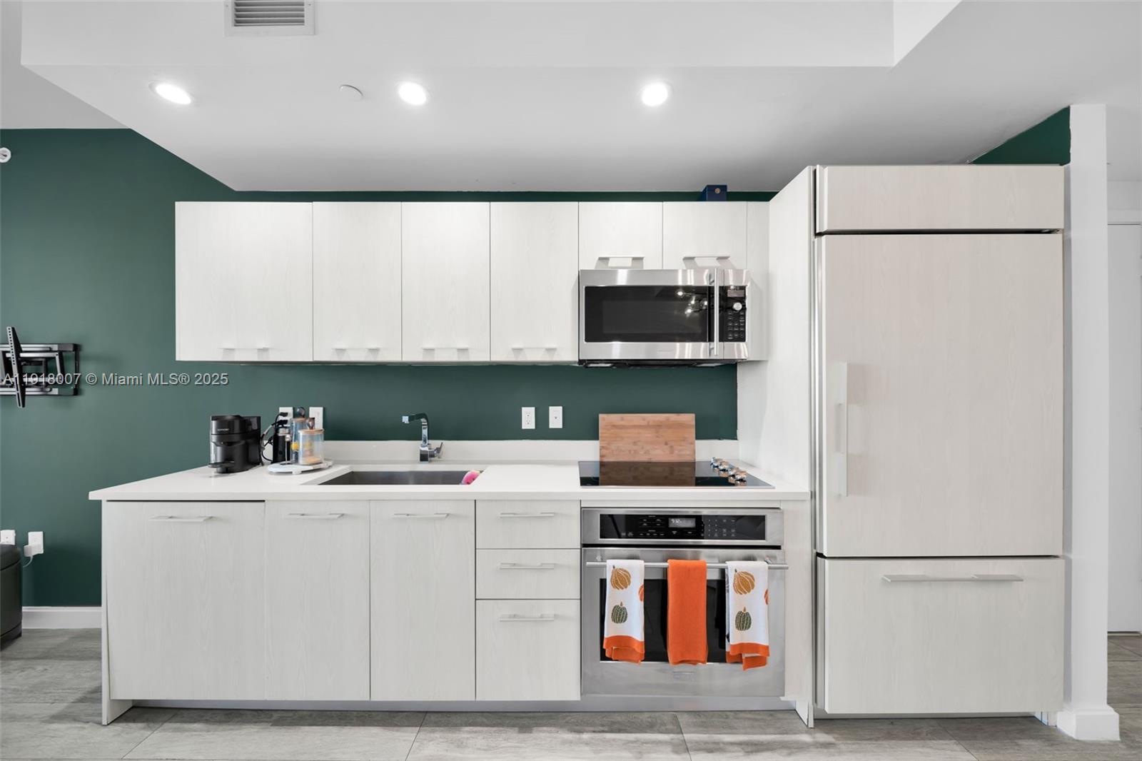 A modern kitchen features white cabinetry, stainless steel appliances, and a dark green backsplash — 45 SW 9th St # 3909, Miami FL 33130, MIAMI, FL