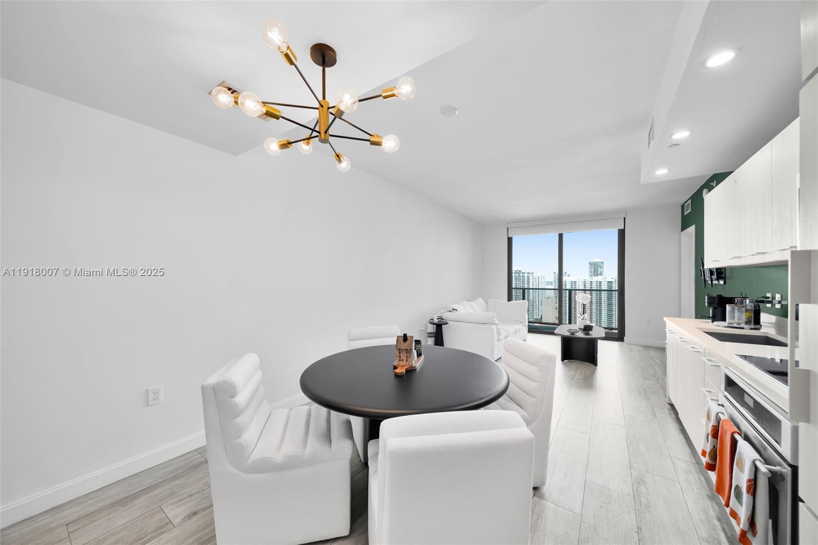 A modern dining area features a round black table, white chairs, and a sputnik chandelier — 45 SW 9th St # 3909, Miami FL 33130, MIAMI, FL