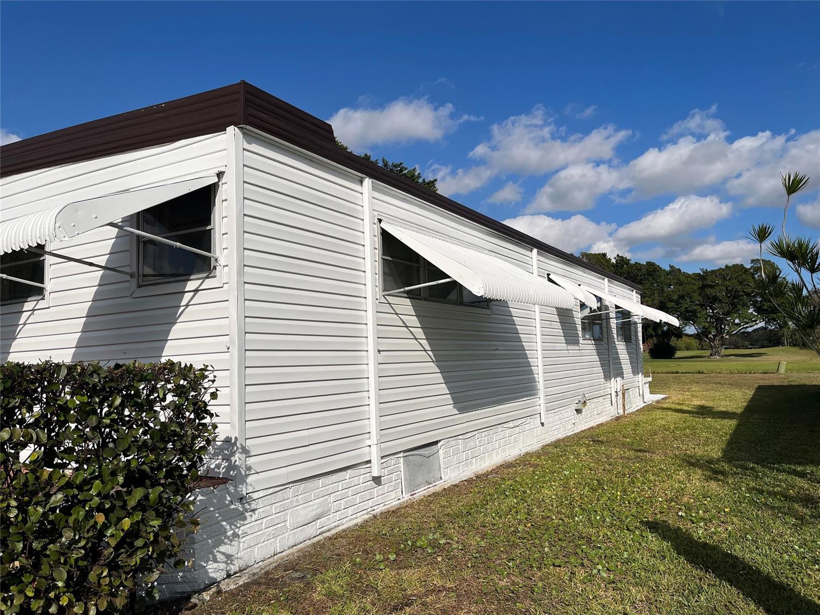The exterior of a white mobile home features metal window awnings and a brick base — 2196 SW 83rd Avenue, Davie FL 33324, DAVIE, FL
