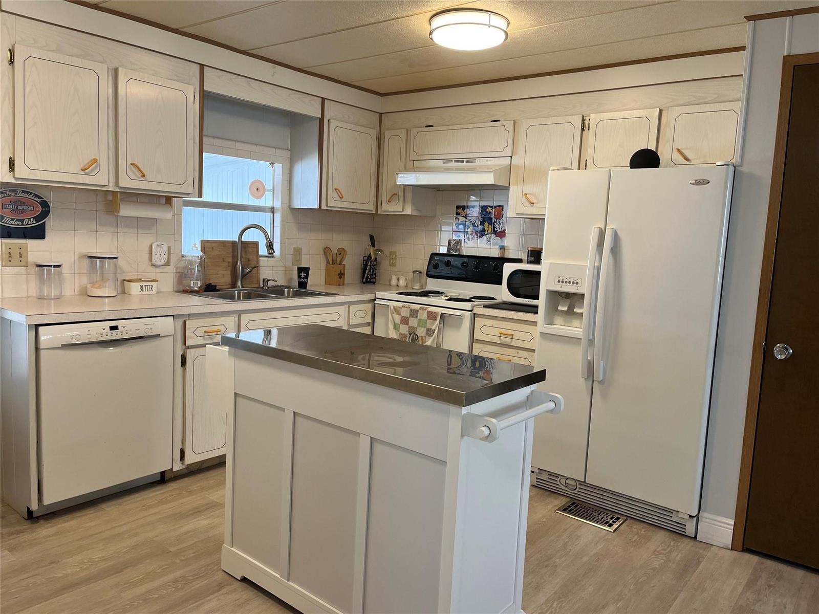 A kitchen features white cabinets, stainless steel appliances, a center island, and light wood flooring — 2196 SW 83rd Avenue, Davie FL 33324, DAVIE, FL