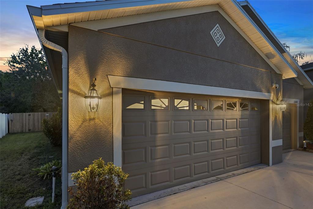 A view of a house exterior featuring a beige garage door and a wall-mounted lantern — 12626 JILLIAN CIRCLE, HUDSON, FL