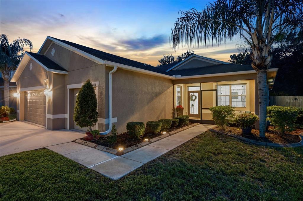 A single-story house with a tan stucco exterior, a two-car garage, and a screened entryway — 12626 JILLIAN CIRCLE, HUDSON, FL