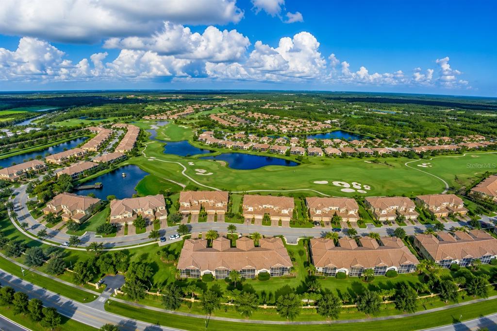 An aerial view shows a residential community with townhomes surrounding a golf course and ponds — 8361 MIRAMAR WAY, LAKEWOOD RANCH, FL