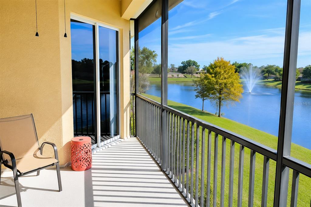A screened-in balcony overlooks a lake with a fountain and a grassy lawn — 8361 MIRAMAR WAY, LAKEWOOD RANCH, FL