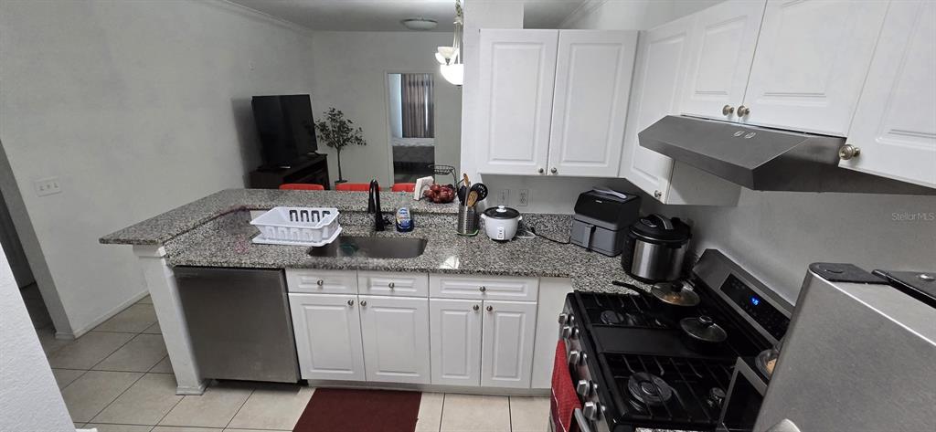 A kitchen features white cabinets, granite countertops, stainless steel appliances, and a breakfast bar — 3379 S KIRKMAN ROAD UNIT 1015, ORLANDO, FL