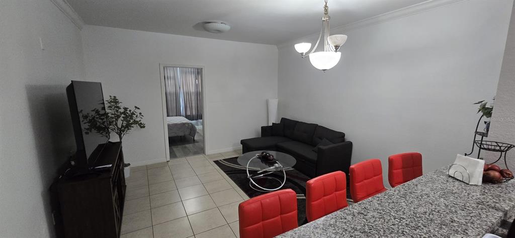 A living room and dining area feature a black sectional, glass coffee table, and red chairs — 3379 S KIRKMAN ROAD UNIT 1015, ORLANDO, FL
