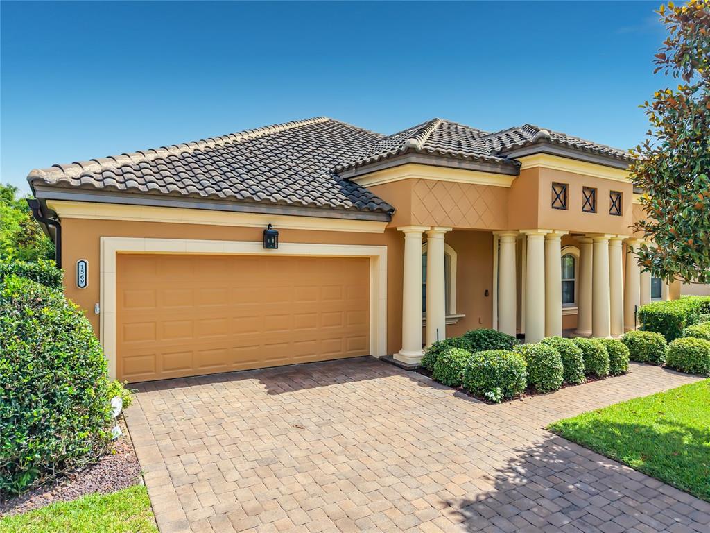 A single-story house with a tan stucco exterior, tile roof, and a paved driveway — 1569 KATIE COVE, SANFORD, FL