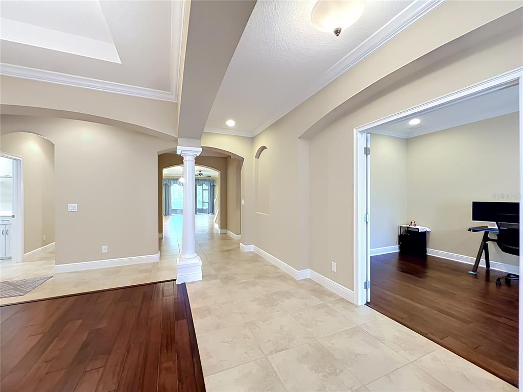 A tiled hallway connects a dark wood-floored office to a living area with a column — 1569 KATIE COVE, SANFORD, FL