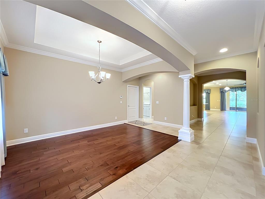 A dining room with dark wood flooring features a tray ceiling and a white column — 1569 KATIE COVE, SANFORD, FL