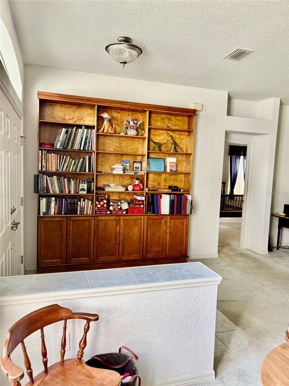 A room features a large wooden built-in bookshelf, a tiled half-wall, and a wooden chair — 8680 SW 209TH COURT, DUNNELLON, FL