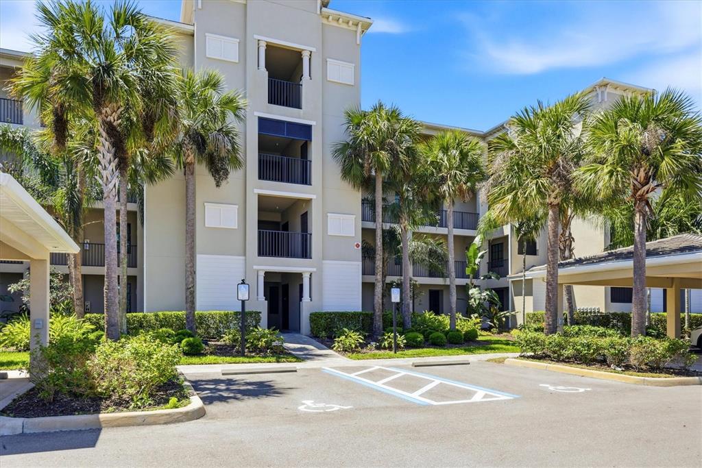 A multi-story apartment building features balconies, palm trees, and a paved parking lot — 17626 GAWTHROP DRIVE UNIT 208, BRADENTON, FL