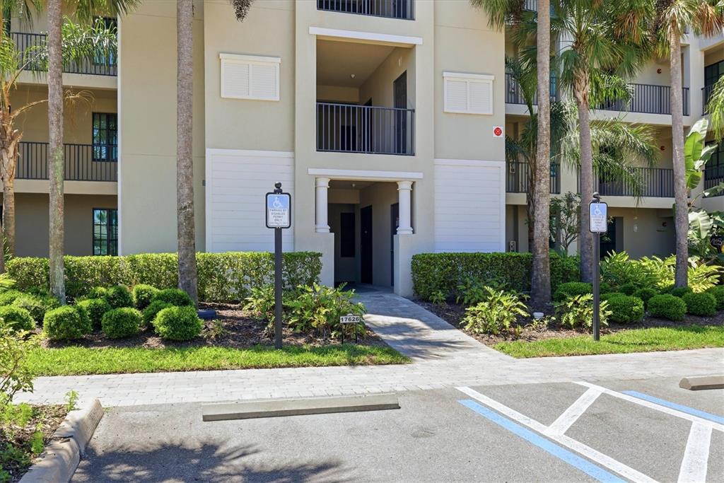 An exterior view of a multi-story apartment building with accessible parking spaces in front — 17626 GAWTHROP DRIVE UNIT 208, BRADENTON, FL