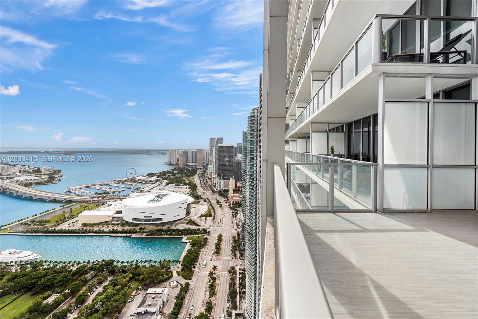A high-rise balcony overlooks a city skyline, a stadium, and a bay with a bridge — 1100 Biscayne Blvd # 5705, Miami FL 33132, MIAMI, FL