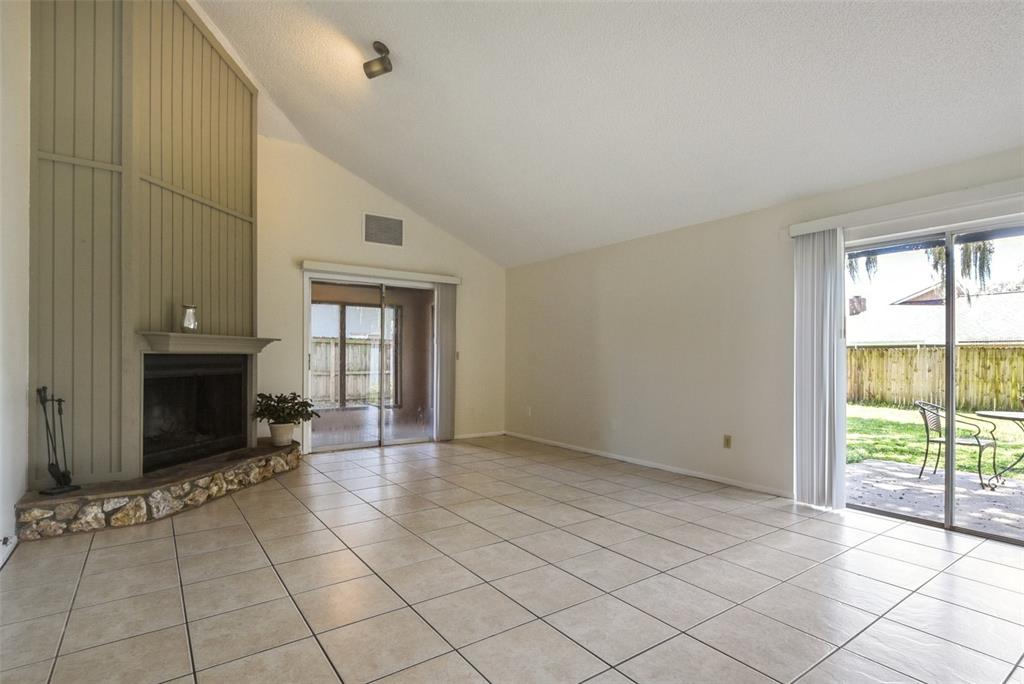 A living room features tile flooring, a stone-based fireplace, and two sliding glass patio doors — 309 REDWING WAY, CASSELBERRY, FL