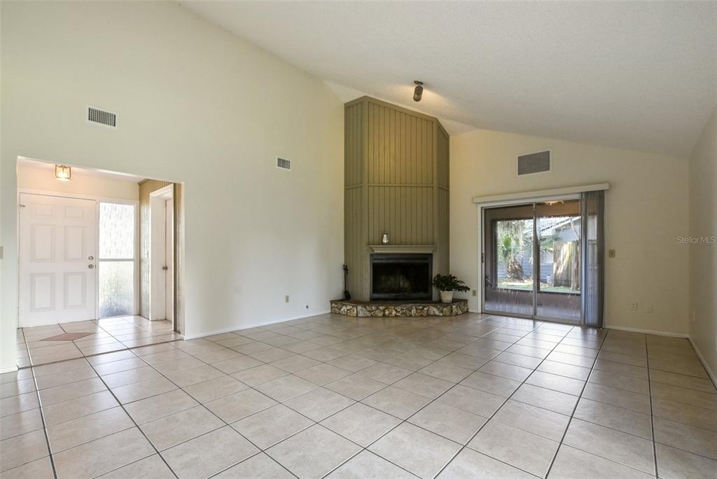 A living room with tile floors, a vaulted ceiling, and a corner fireplace — 309 REDWING WAY, CASSELBERRY, FL