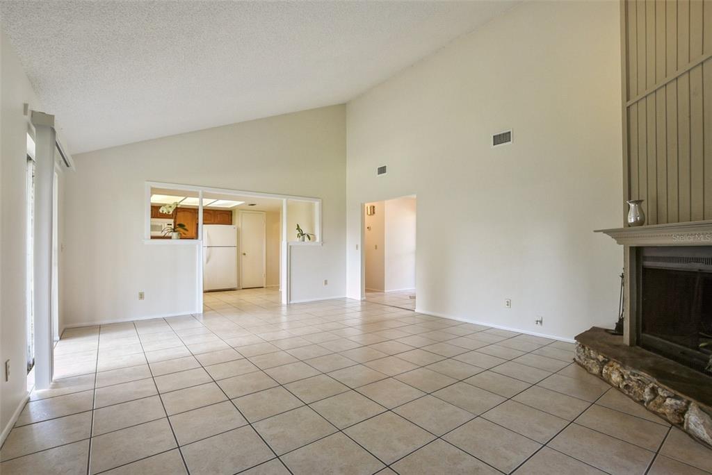 A living room with vaulted ceilings, tile flooring, and a stone fireplace — 309 REDWING WAY, CASSELBERRY, FL