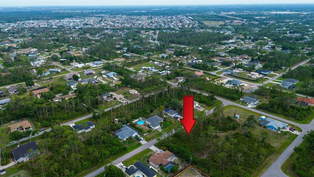 An aerial view shows a vacant, wooded residential lot marked by a large red arrow — 5263 ELLSWORTH TERRACE, PORT CHARLOTTE, FL