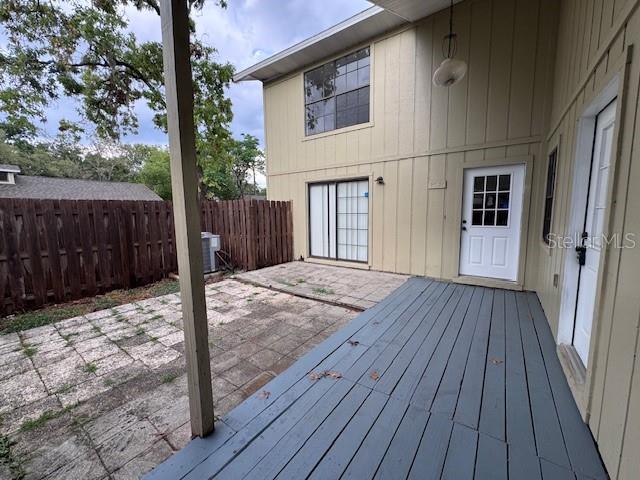 A gray wooden deck leads to a patio area beside a two-story house exterior — 4546 LIGHTHOUSE CIRCLE UNIT 14, ORLANDO, FL