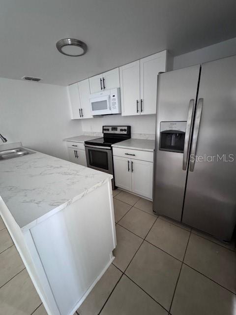 A kitchen features white cabinets, stainless steel appliances, and a marble-patterned island countertop — 4546 LIGHTHOUSE CIRCLE UNIT 14, ORLANDO, FL