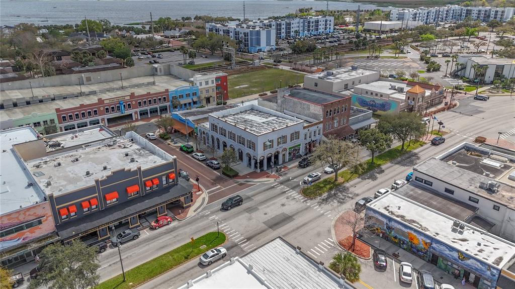 An aerial view shows a city street intersection lined with commercial buildings and parked cars — 24 BROADWAY AVENUE UNIT A, KISSIMMEE, FL