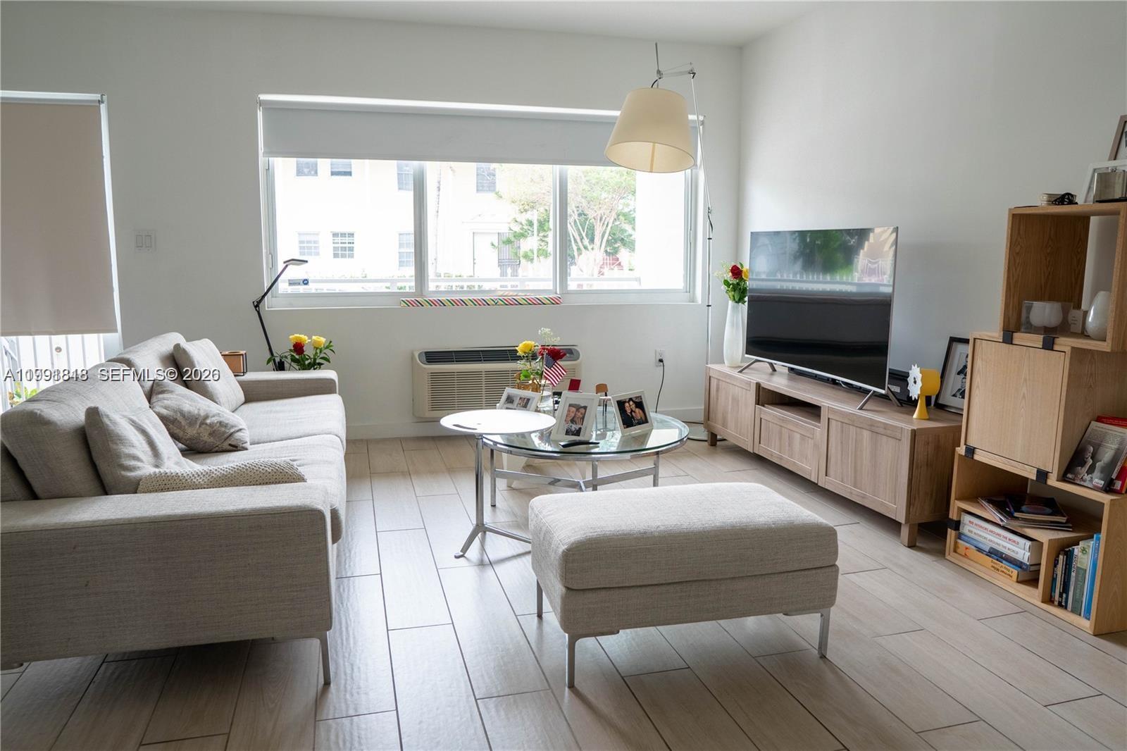 A living room features a beige sofa, a glass coffee table, and a wooden media console — 625 77th St # 2, Miami Beach FL 33141, MIAMI BEACH, FL