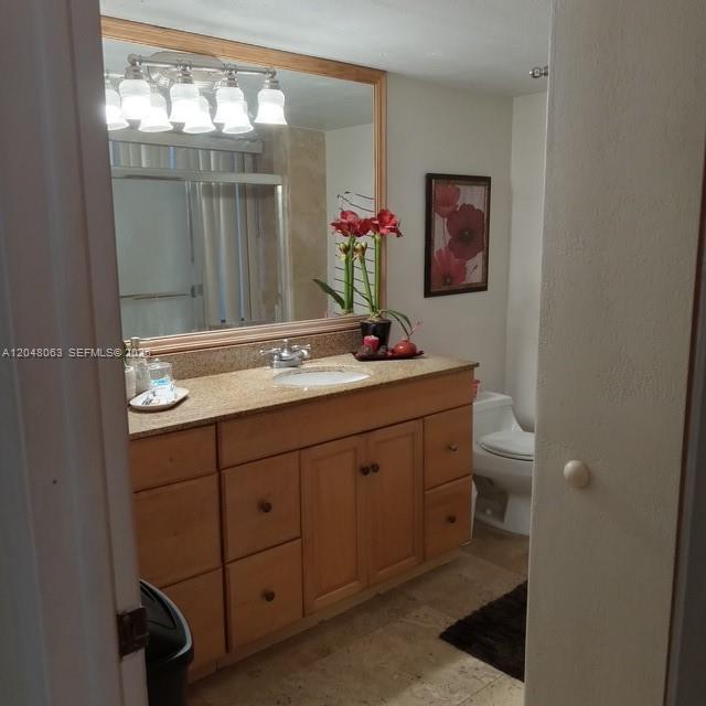 A bathroom features a wooden vanity with a granite countertop, a large mirror, and a toilet — 8301 SW 157th Ave # 206, Miami FL 33193, MIAMI, FL