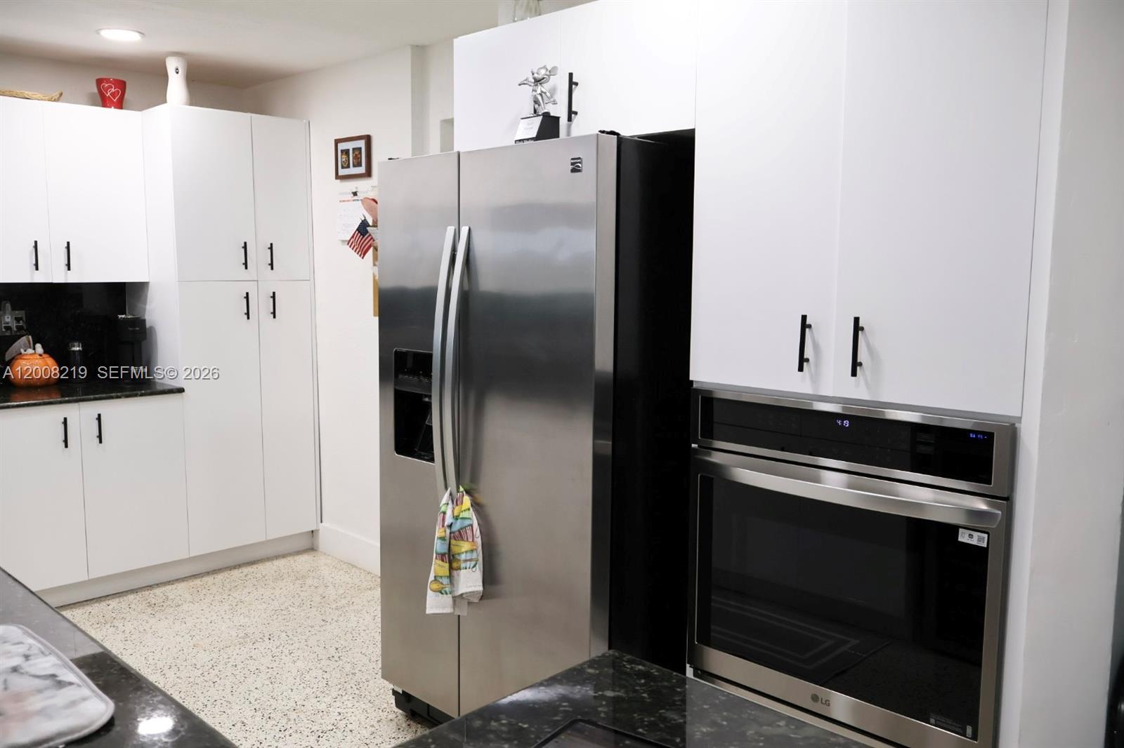 A kitchen features white cabinetry, stainless steel appliances, and dark granite countertops — 11206 SW 1st St, Sweetwater FL 33174, SWEETWATER, FL
