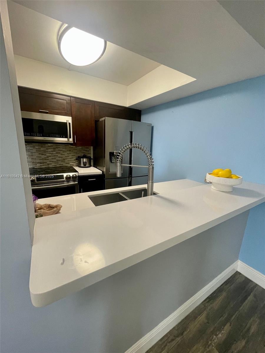 A kitchen features dark wood cabinets, stainless steel appliances, and a white quartz breakfast bar — 11800 SW 18th St # 4, Miami FL 33175, MIAMI, FL