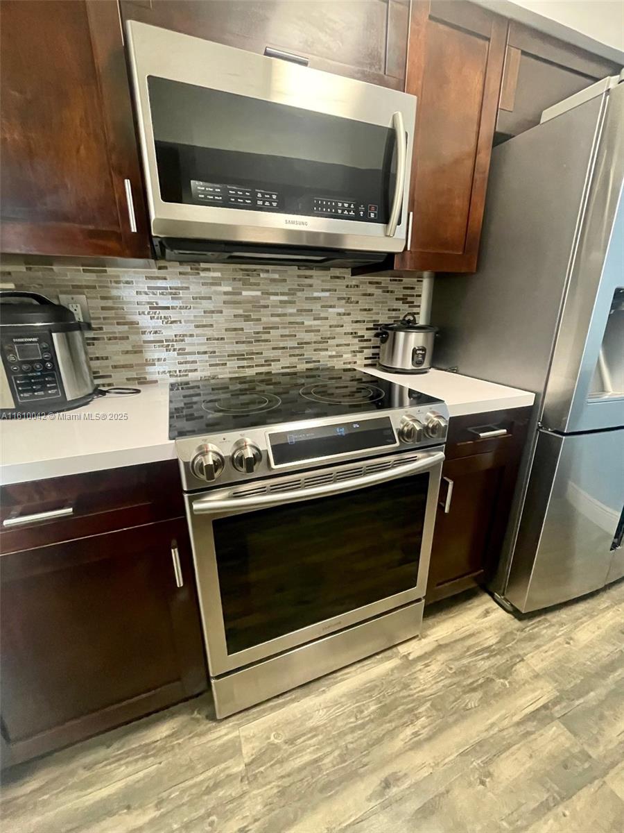 A kitchen features dark wood cabinets, stainless steel appliances, and a mosaic tile backsplash — 11800 SW 18th St # 4, Miami FL 33175, MIAMI, FL
