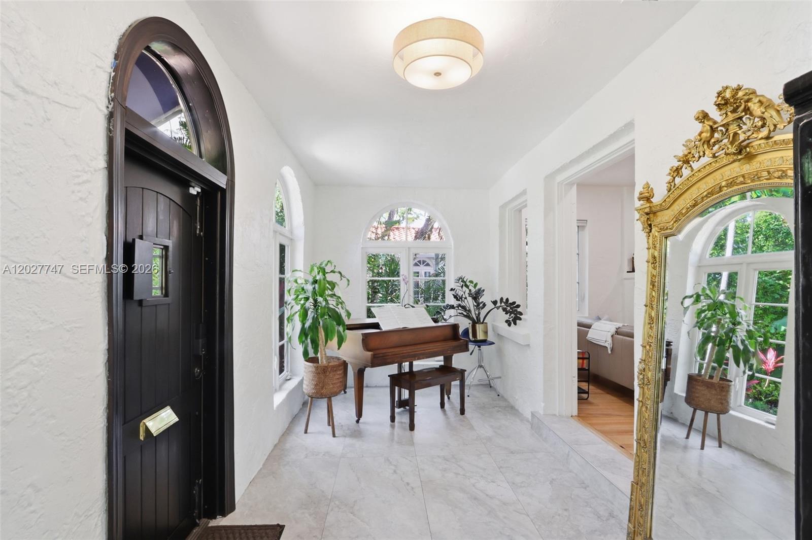 A bright entryway features a grand piano, white walls, tile floors, and an ornate gold mirror — 1215 Madrid St, Coral Gables FL 33134, CORAL GABLES, FL