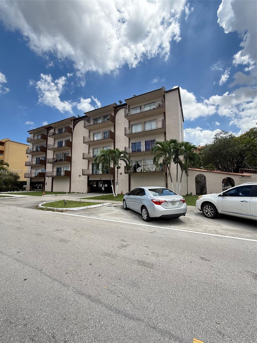 A multi-story apartment building with balconies stands behind a paved parking lot — 1950 W 54th St # 115, Hialeah FL 33012, HIALEAH, FL
