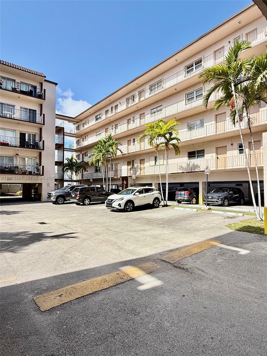 An exterior view of a multi-story apartment building with covered parking and palm trees — 1950 W 54th St # 115, Hialeah FL 33012, HIALEAH, FL