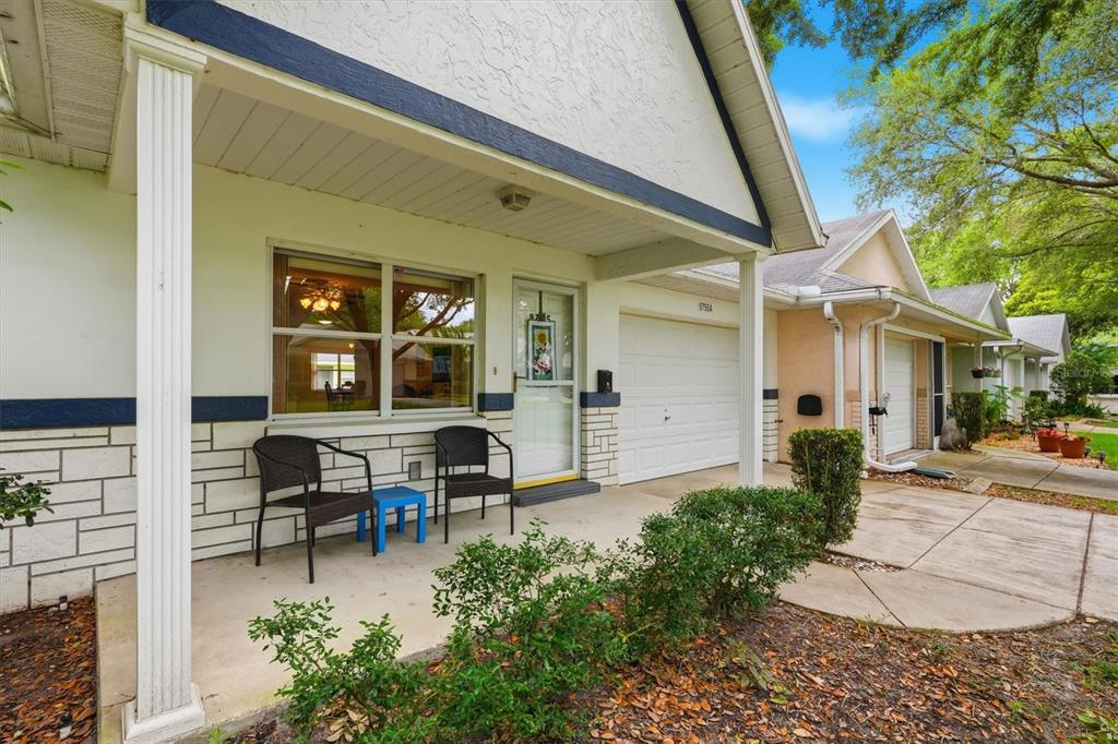 A front porch with two chairs and a blue table sits before a white house — 9755 SW 94TH TERRACE UNIT A, OCALA, FL
