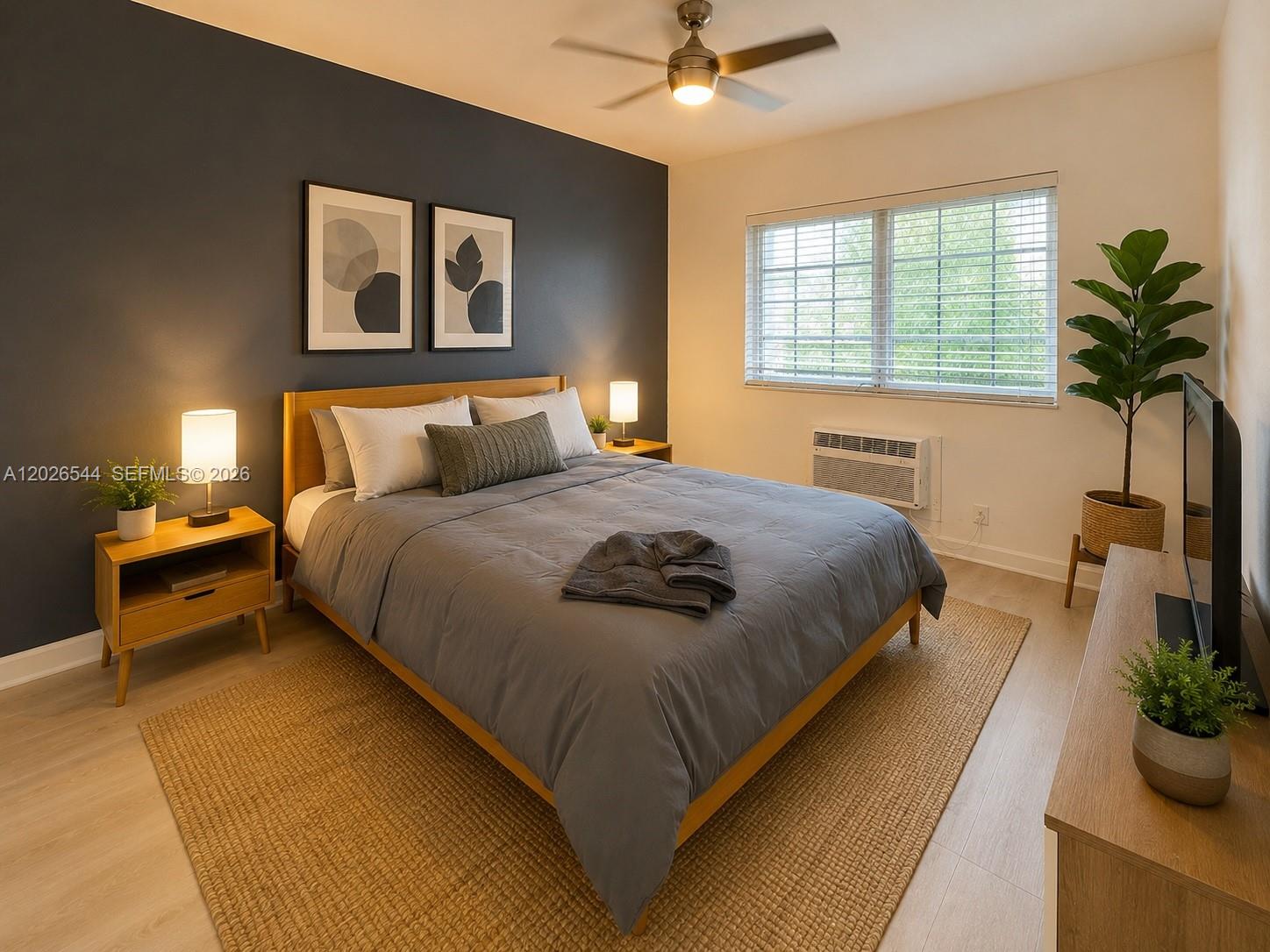A bedroom features a dark accent wall, a wooden bed frame, and a large window — 836 10th St # 7, Miami Beach FL 33139, MIAMI BEACH, FL