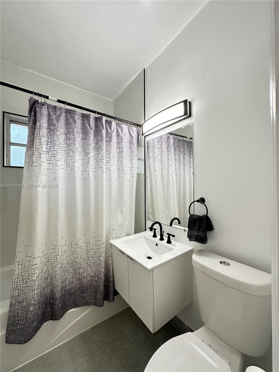 A bathroom features a white vanity, a toilet, and a shower with a patterned curtain — 836 10th St # 7, Miami Beach FL 33139, MIAMI BEACH, FL