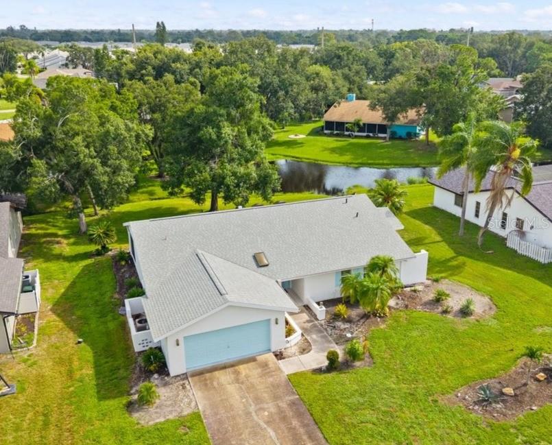 An aerial view shows a single-story house with a light blue garage and a pond — 5438 DOMINICA CIRCLE, SARASOTA, FL