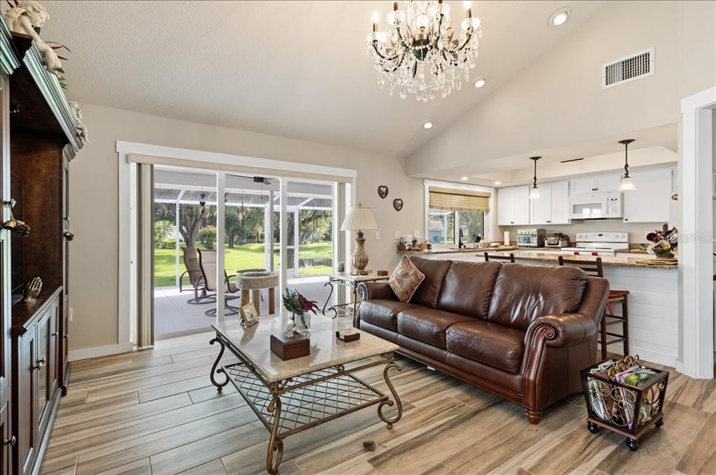 A living room features brown leather sofas, a wood entertainment center, and tile flooring — 5438 DOMINICA CIRCLE, SARASOTA, FL