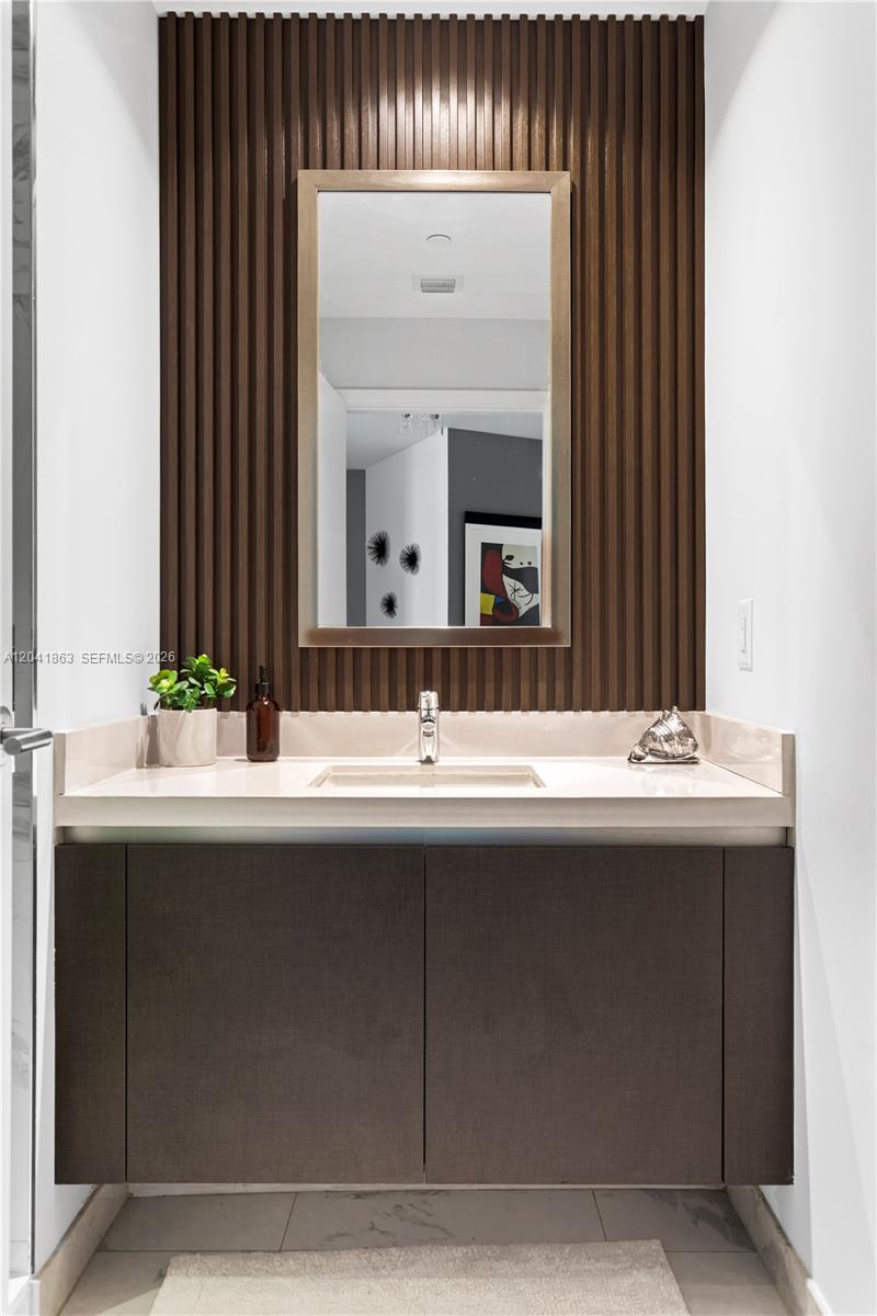 A bathroom vanity features a slatted wood accent wall, a rectangular mirror, and dark cabinetry — 851 NE 1st Ave # 3900, Miami FL 33132, MIAMI, FL